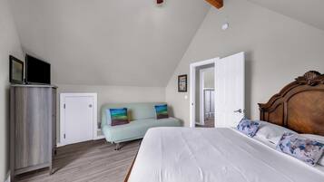 A bedroom with a bed, a sofa, a wardrobe, and a ceiling fan.