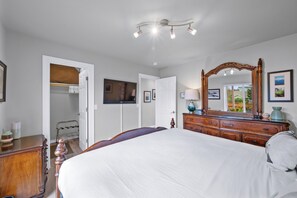 A bedroom with a large bed, a dresser, a mirror, and a wardrobe. - Sunkissed 3BR - Oceanview Beach Home (Pacific Beach)