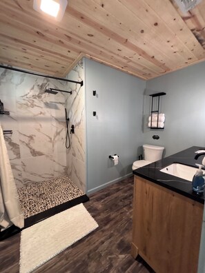 Een moderne badkamer met douche, toilet en wastafel.