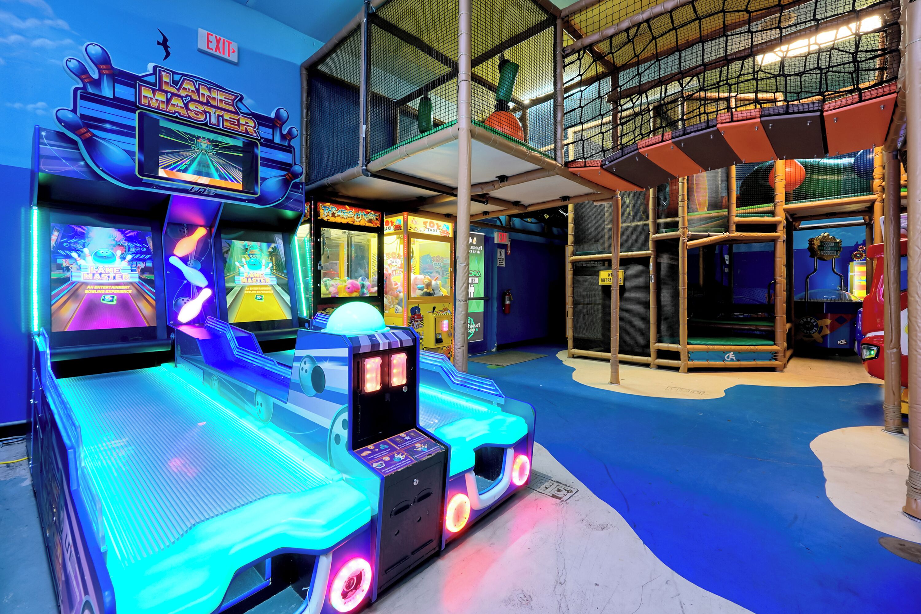 Une salle d’arcade lumineuse, dotée de nombreuses pistes de bowling et de machines à pinces.