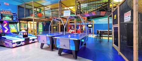 An indoor play area with various arcade games, a foosball table, and a pool table.