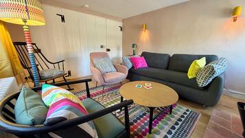 A living room with a sofa, armchairs, a coffee table, and a patterned rug.