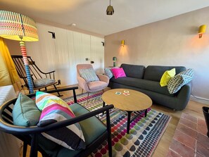 A living room with a sofa, armchairs, a coffee table, and a patterned rug.