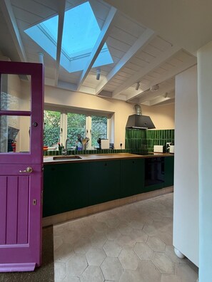 A kitchen with a skylight, green cabinets, and a purple door.