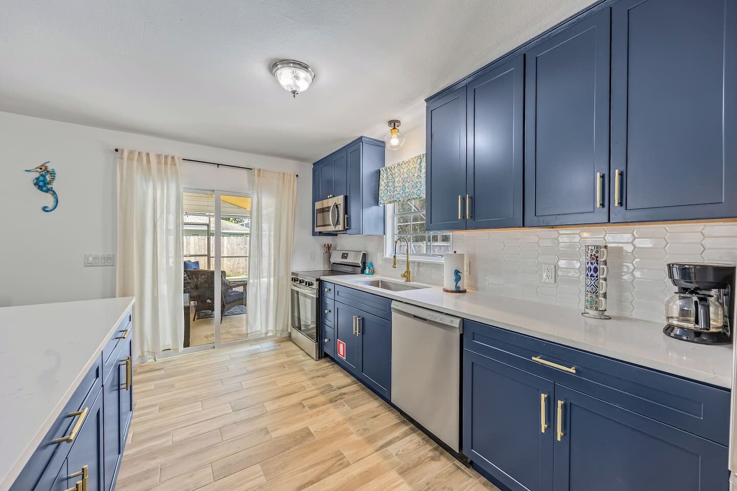 A modern kitchen with dark blue cabinets, a white countertop, and a wooden floor.