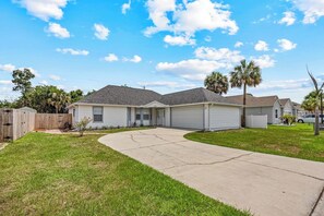A residential area with a two-story house, a driveway, and a wooden fence. - Pool Retreat | Near USSSA | Beach & Launches (Rockledge)