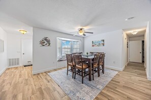 A dining area with a wooden table and chairs, a ceiling fan, and a window with blinds. - Pool Retreat | Near USSSA | Beach & Launches (Rockledge)