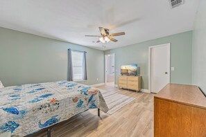 A bedroom with a bed, a dresser, a television, a ceiling fan, and a window with blinds. - Pool Retreat | Near USSSA | Beach & Launches (Rockledge)