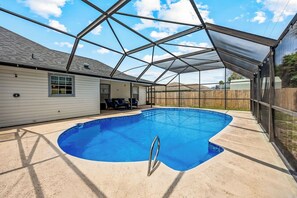 A swimming pool with a glass enclosure, a covered patio area, and a view of a residential building. - Pool Retreat | Near USSSA | Beach & Launches (Rockledge)