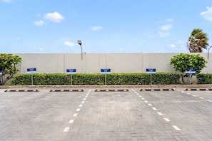 A parking area with multiple reserved parking signs, a paved surface, and a hedge in the background. - AL318 -Resort Pool-Beach Tennis court- 2BR+ condo-Close to Palm Beach (Noord)