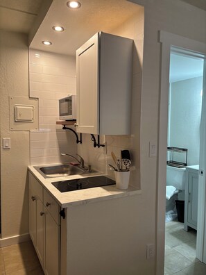 A compact kitchen with white cabinetry, a double sink, and a built-in microwave.