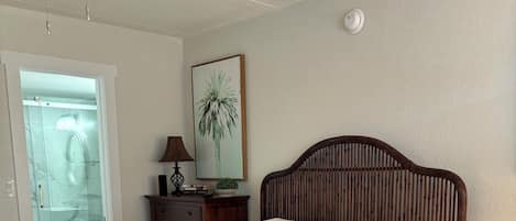 Un lit bien fait, avec du linge de lit et des serviettes blanches, une tête de lit en bois, une petite table de chevet avec une lampe et une chaise.