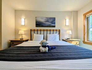 Habitación de hotel con una cama, dos lámparas de noche, un cuadro en la pared y una ventana con vistas.