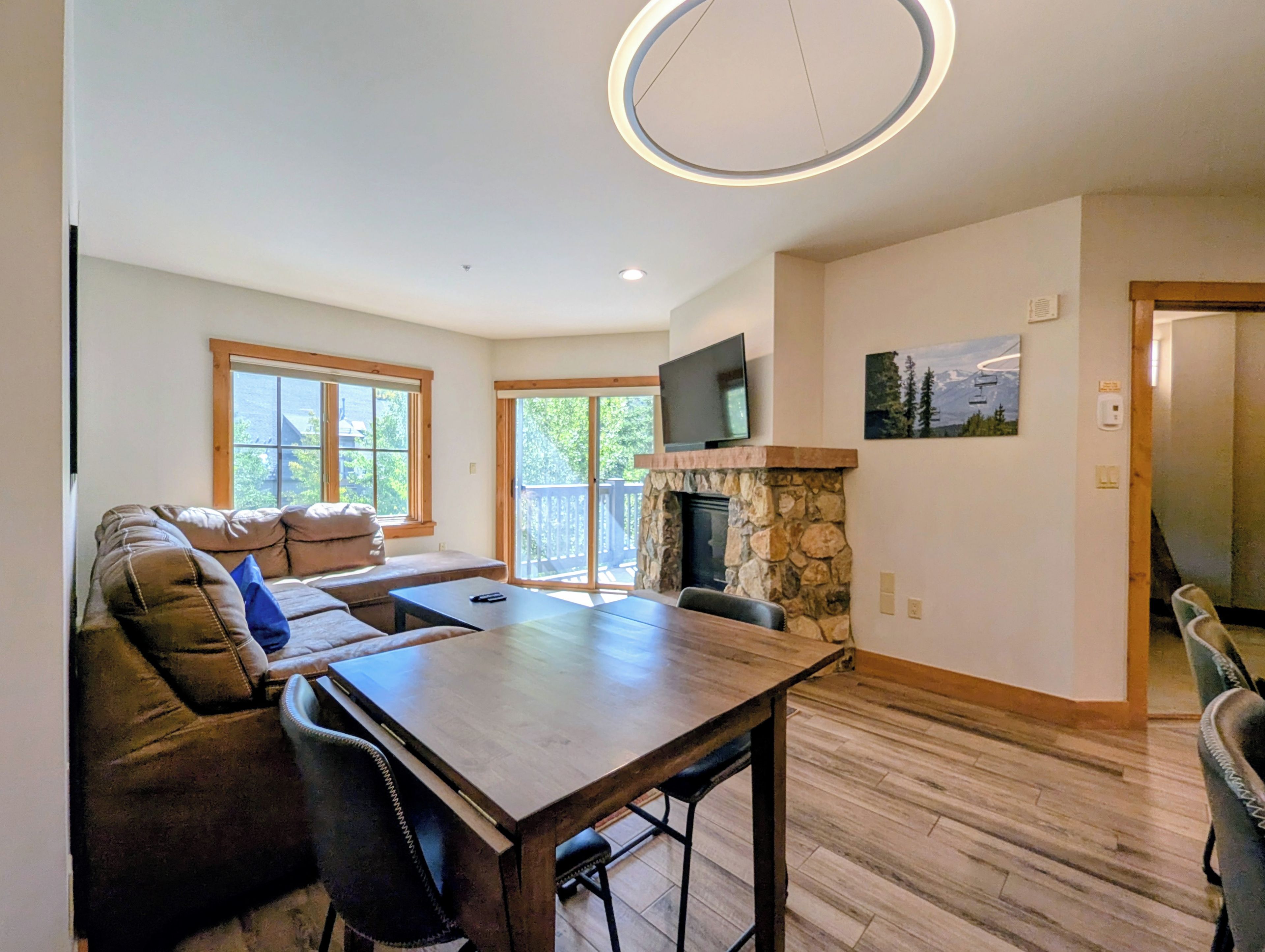 A spacious living area with a stone fireplace, a large wooden dining table, and a comfortable seating arrangement.