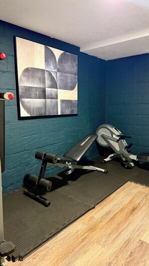 A gym with exercise equipment, a blue wall, and a painting. - Lux 2BR Home Near Navy Base, AbbVie/Abbott, Six Flags, Beach (Waukegan)