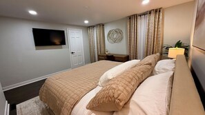 A bedroom with a bed, a television, a door, curtains, and a wall decoration. - Lux 2BR Home Near Navy Base, AbbVie/Abbott, Six Flags, Beach (Waukegan)