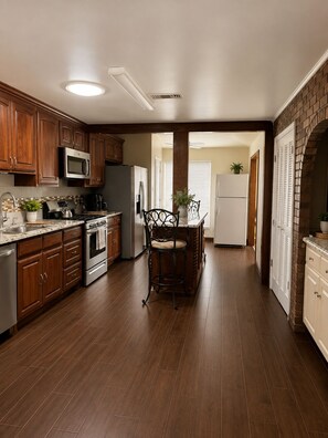 A kitchen with wooden cabinets, a stainless steel refrigerator, a microwave, and a stove.