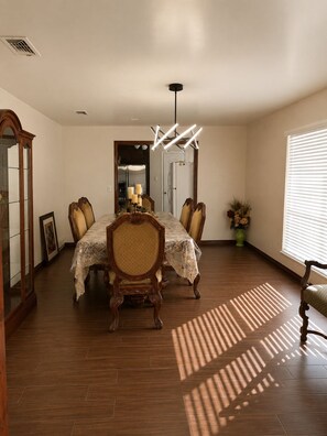 A dining room with a wooden table and chairs, a chandelier, and a view of the kitchen through an open doorway. - Rustic TX Escape in DFW, Near Stadium, Airport & Downtown (Fort Worth)