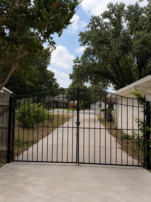 A gated driveway leading to a residential property with a house and garage. - Spacious Getaway : 4BR-10Guest House Near AT&T Stadium, DFW Airport & Stockyards (Fort Worth)