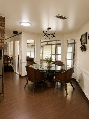 A dining area with a glass table, wooden chairs, and a ceiling light fixture.
