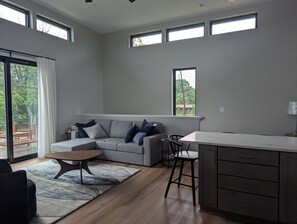 Un espacio habitable moderno con un sofá seccional, una mesa de comedor y una zona de cocina.