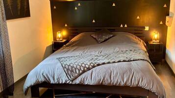 A modern bedroom with a dark headboard, two bedside lamps, a patterned rug, and a geometric floor design.