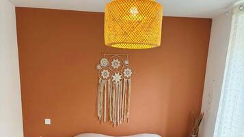A bedroom with a large bed, a hanging light fixture, and a wall decoration.