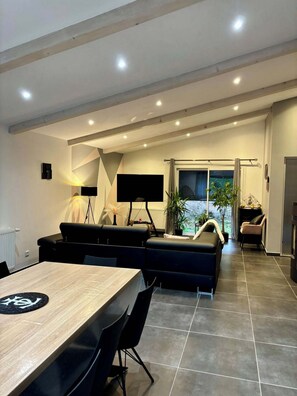 Una sala moderna con televisor grande, zona de estar y una mesa de comedor.