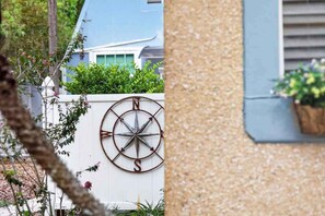 A wall-mounted compass and a potted plant on a building facade. - King Davis Cottage | Fenced In, Downtown (St. Augustine)