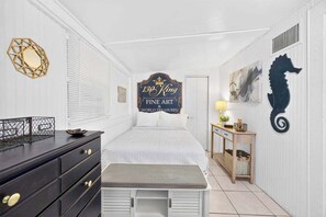 A hotel room with a bed, a dresser, a nightstand, a wall-mounted sign, and a decorative seahorse. - King Davis Cottage | Fenced In, Downtown (St. Augustine)