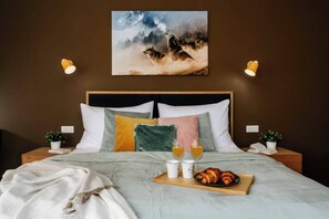 A bedroom with a bed, pillows, bedside tables, a tray with croissants and drinks, and a painting on the wall. - Spacious 2BR Vršovice | AC • Netflix • Balcony (Prague 10)