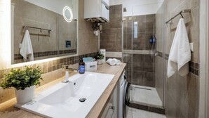 Un baño moderno con un espejo grande, un lavabo, una ducha y un perchero para toallas.
