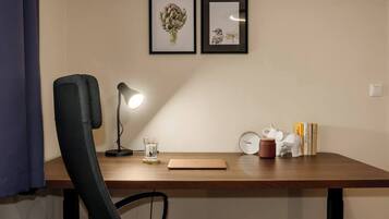 A workspace with a desk, chair, lamp, glass, clock, books, and decorative items.