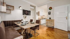 Un comedor moderno con una mesa de madera, asientos acolchados y una cocina al fondo.