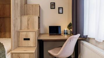 A room with a wooden desk, a laptop, a chair, and a radiator.