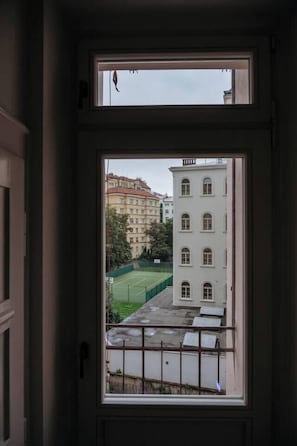 Blick durch ein Fenster auf ein Gebäude und einen Tennisplatz.