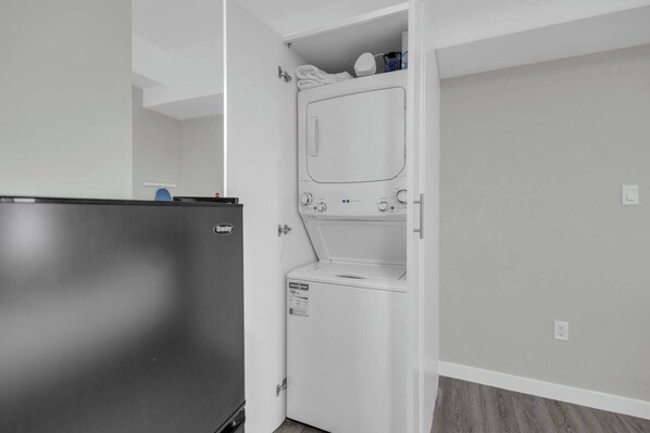 A compact kitchen with a refrigerator, a washing machine, and a small countertop area.