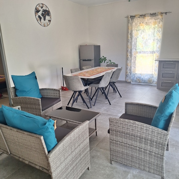 A dining area with a table and chairs, a refrigerator, and a window with curtains.