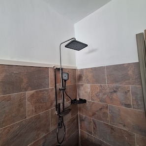 Una ducha con cabezal de ducha de mano y otro cabezal fijo en la pared.