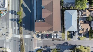 An aerial view of a parking lot with cars, a stop sign, and a building with a distinctive roof. - Lovely 4-bedroom condo in Dewey Beach perched above all the action! (Dewey Beach)