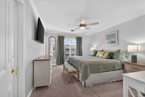 A bedroom with a bed, a desk, a chair, a television, a ceiling fan, and a window with curtains. - Lovely 4-bedroom condo in Dewey Beach perched above all the action! (Dewey Beach)