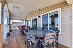 A covered patio with a round table and chairs, a railing, and a view of the street. - Lovely 4-bedroom condo in Dewey Beach perched above all the action! (Dewey Beach)