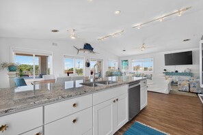 A spacious kitchen with a large island, white cabinetry, and a view to the outdoors. - Lovely 4-bedroom condo in Dewey Beach perched above all the action! (Dewey Beach)