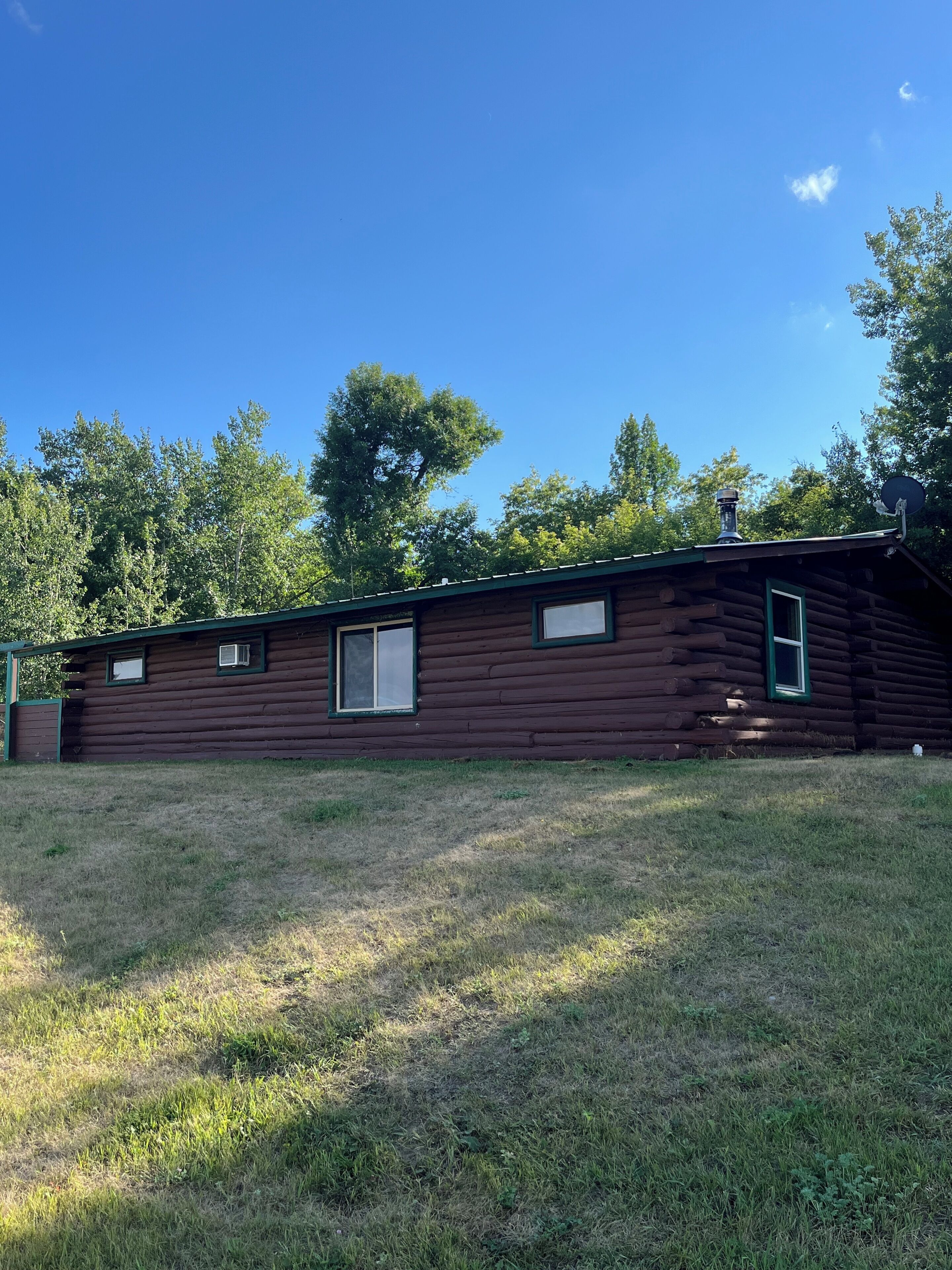 A log cabin with a chimney, a satellite dish, and a small window.