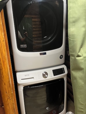 A stacked washer and dryer unit with a 10-year warranty sticker. - Charming 2-bedroom log cabin with AC by Lake Metigoshe (Bottineau)