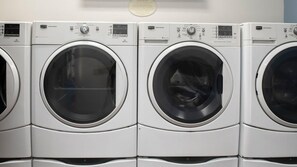 A row of identical front-loading washing machines in a commercial setting.