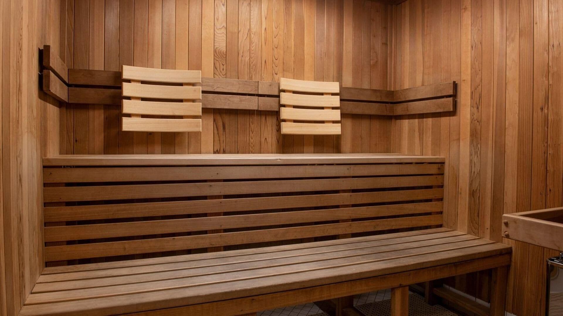 Een houten sauna bank met gesleufde rugleuning en een zitbank, tegen een houten wand.