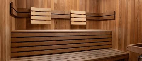 A wooden sauna bench with slatted backrests and a bench seat, set against a wooden wall.
