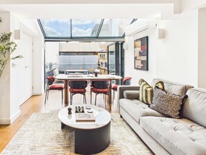 Ein modernes Wohnzimmer mit einem runden Couchtisch, einer Couch und einem Essbereich mit Stühlen.
