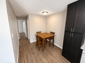 A dining area with a wooden table and chairs, a black cabinet, and a hallway leading to another room. - Perfect 2-bedroom apartment with AC in vibrant Arlington (Arlington)